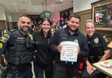 Four Officers posing with Tip A Cop donation bucket 